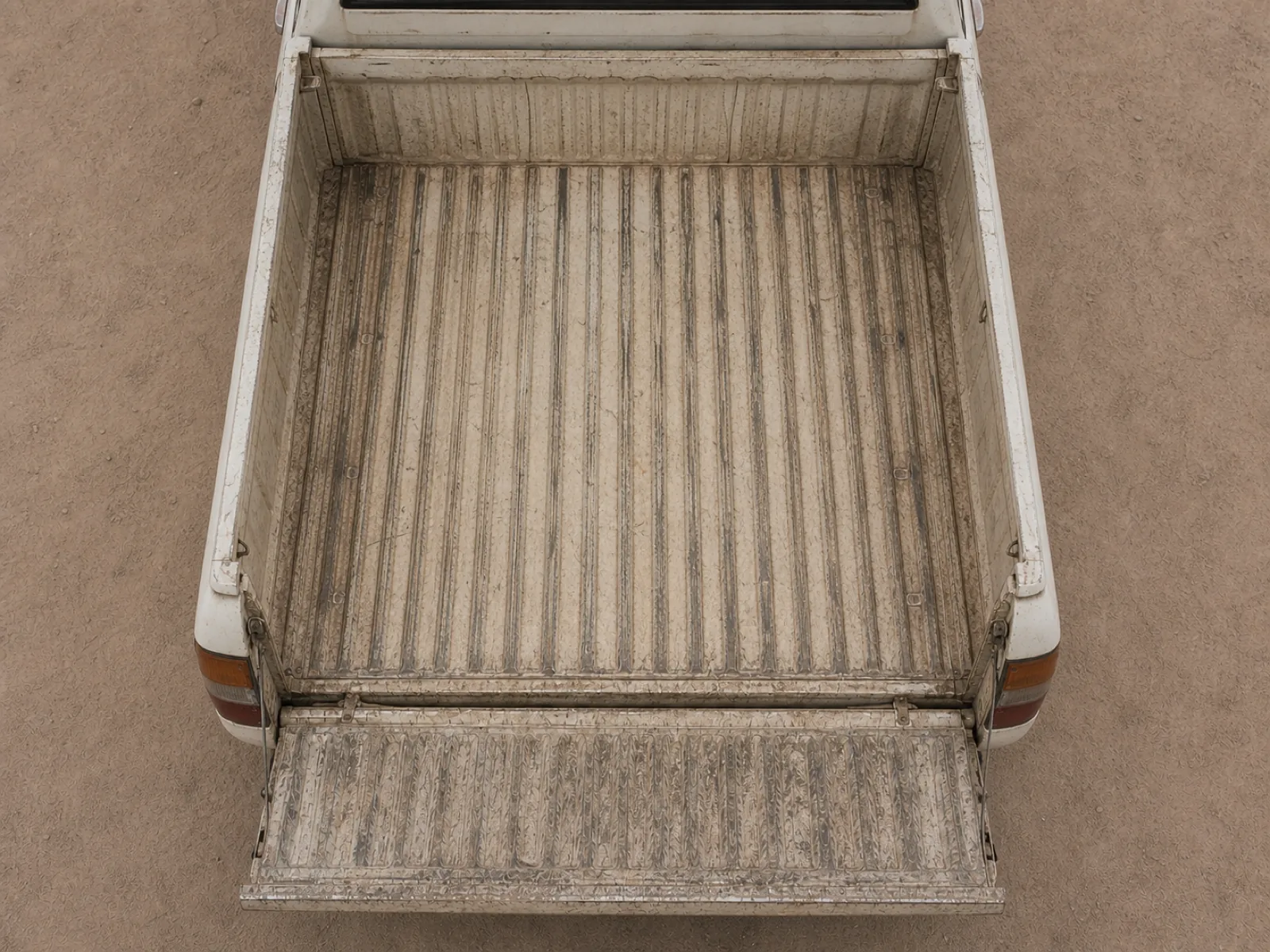 An empty pickup bed photographed straight down from above, tailgate down, clean but visibly used